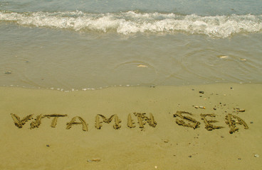 Words Vitamin Sea written on the sand