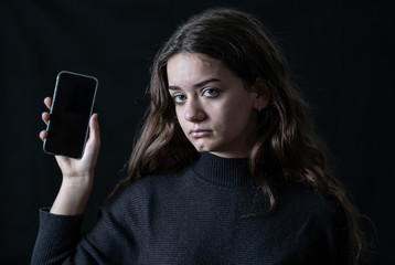 Portrait of sad young girl on mobile suffering harassment online