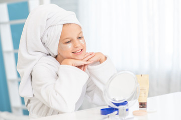 Young girl admires her reflection in the mirror