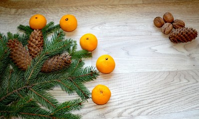 Fototapeta na wymiar Spruce branches, cones and tangerines with nuts on the background