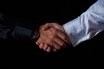 two male businessmen in black and white shirt shake hands, black background, studio shooting
