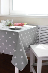 white plate on the table with flowers in the sunlight
