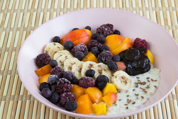 Oatmeal with bananas, apricots, blueberries, blackberries, chocolate paste and sesame seeds