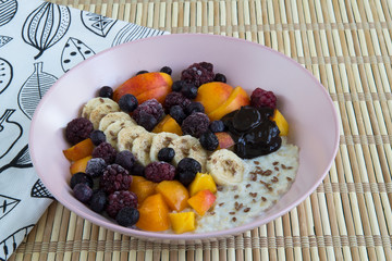 Oatmeal with bananas, apricots, blueberries, blackberries, chocolate paste and sesame seeds