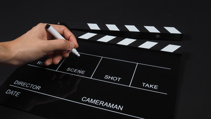 Fototapeta na wymiar Clapperboard or clap board or movie slate with hand holding pen use in video production ,film, cinema industry on black background.