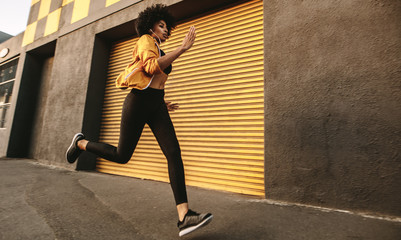Sporty young woman sprinting outdoors