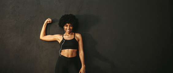 Obraz premium Fitness woman flexing muscles and smiling
