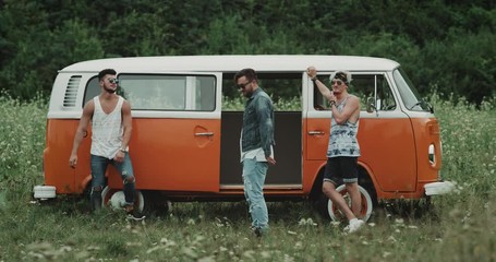 Three dancers have a great time together at the picnic, moving very charismatic in front of a retro van
