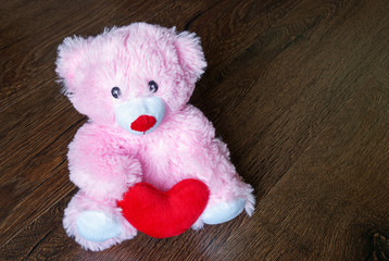 toy teddy with heart isolated on wooden background