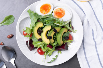 Fresh healthy vegetable salad with egg, tomato, avocado, spinach, lettuce in plate on table background.