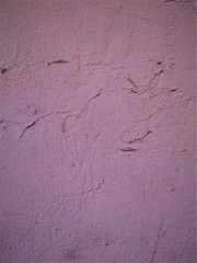 Old plaster on the wall, dark pink. The coating is uneven, with surges.