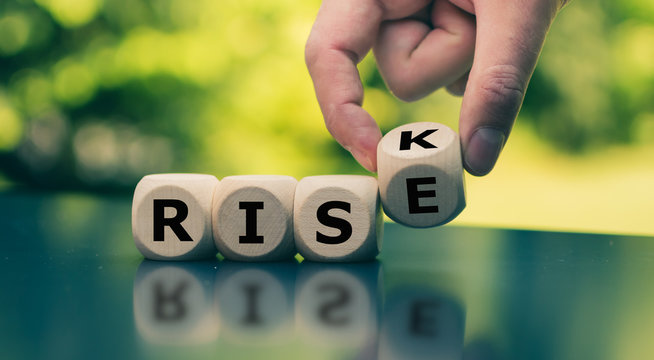 Hand turns a cube and changes the word "risk" to "rise".
