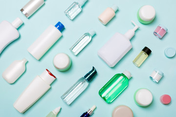 Top view of different cosmetic bottles and container for cosmetics on blue background. Flat lay composition with copy space