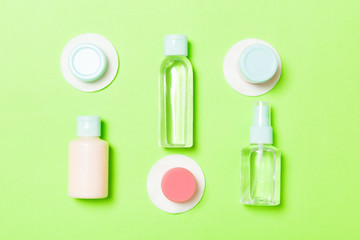 Set of travel size cosmetic bottles on green background. Flat lay of cream jars. Top view of bodycare style concept