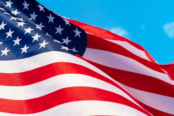 Fototapeta premium American flag waving in the wind against blue sky