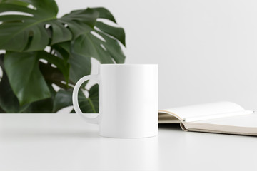 Mug mockup with workspace accessories and a monstera plant.