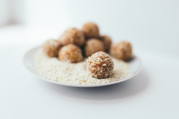 Fruit balls in a nut crumb on a white plate on a blurred background