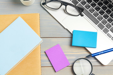 Angled View of laptop Computer Keyboard and glasses with Various Office Supplies on wooden Desk