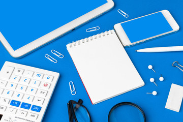 Flat lay, top view of blue office table desk. Workspace with blank note book,  office supplies