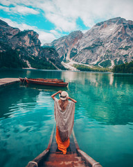Girl in a hat on the background of the turquoise lake in mountain. Dolomites Alps, lago di Braies, Italy - obrazy, fototapety, plakaty
