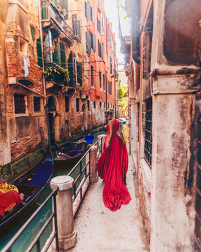 Fototapeta  Girl in red dress at the carnival in Venice at the canal with gondolas