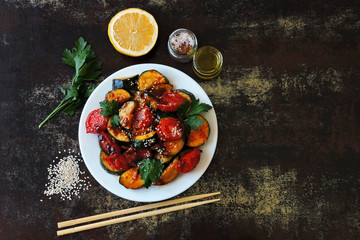 Baked zucchini slices with cherry tomatoes and sesame on a white plate. Vegan dinner Diet food.