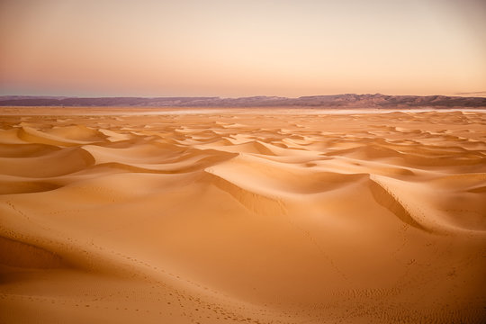 Sandd&uuml;ne bei Sonnenuntergang in der Sahara mit dem Atlas Gebirge im Hintergrund in Marokko