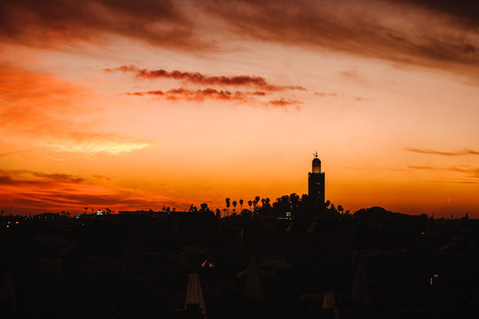 Sonnenuntergang &uuml;ber Marrakesch mit einer Moschee im Hintergrund und dramatischem Himmel