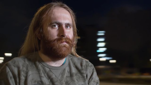 Point of view shot of brutal man while spinning on blurred background at night. He is serious at the biggining and smiling at the end of a clip