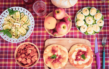 Brunch with colorful checked tablecloth.  Healthy food with vegetables, eggs and pizza. Food and drink