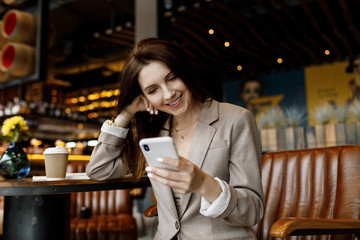 Portrait of young  woman at cafe drinking coffee and using mobile phone