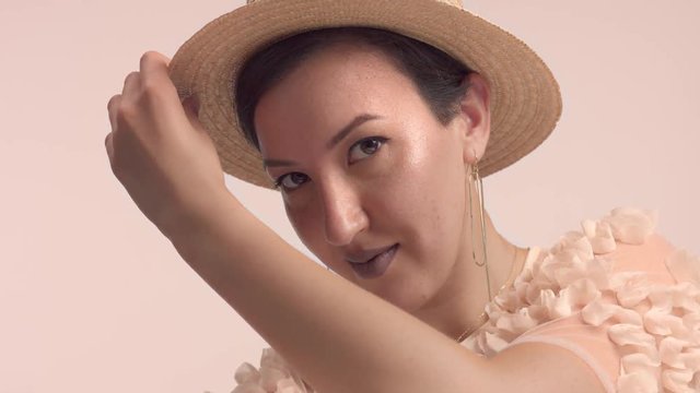 closeup portrait of young model in studio with ideal shiny skin wears a summer hat
