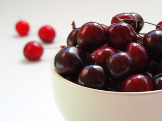 red cherry in a white bowl on a white background. Summer fruits and vitamins.