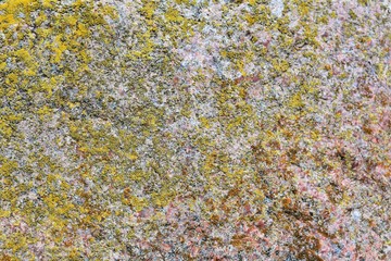 Natural stone background with textured surface and green moss. Pattern mineral with rough structure and yellow lichen. Aging colorful mountain backdrop. Natural stone surface with empty space for text