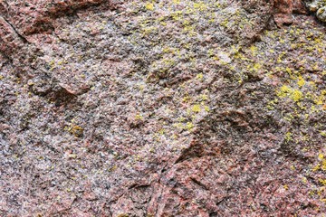 Natural stone background with textured surface and green moss. Pattern mineral with rough structure and yellow lichen. Aging colorful mountain backdrop. Natural stone surface with empty space for text