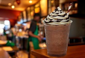 Frappuccino with cream and chocolate sauce on wooden table at cafe - obrazy, fototapety, plakaty