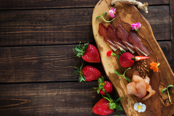 Cold cuts on a plain background, wooden board, strawberries and micro greens. Free place fox text