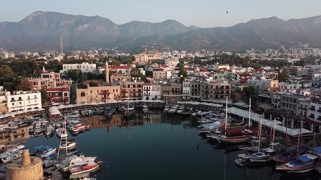 Smooth flight of the drone over the harbor in Kyrenia (Girne) Northern Cyprus. Top view on pleasure yachts, fishing boats and the city on the background of mountains