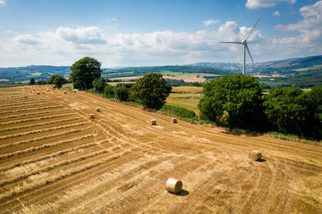Aerial view of Straw bales with a wind turbine on farmland in Wales UK
