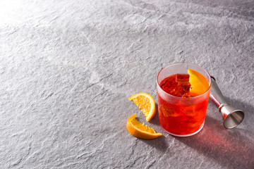 Negroni cocktail with piece of orange in glass on gray background. Copyspace