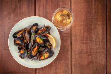 Fototapeta na wymiar Marinara mussels, moules mariniere, with a glass of white wine, shot from the top on a dark rustic wooden background with a place for text