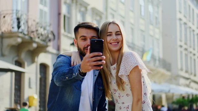 Amazing cheerful young people standing in the middle of urban street talking by viber with somebody and saying hallo