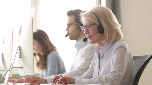 Older business woman wear wireless headset working in customer service
