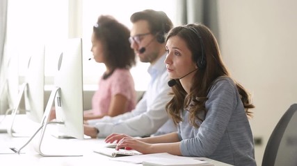 Young woman customer care agent in headset consulting online client