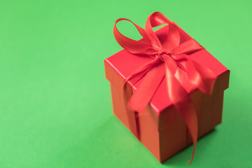 Red square gift box with a bow on a green background
