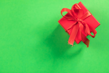Red square gift box with a bow on a green background