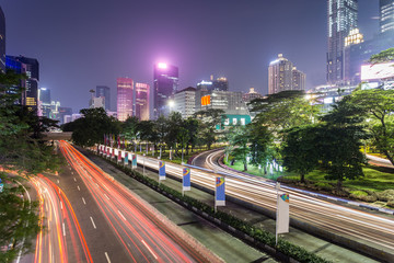 Fototapeta premium Traffic, captured with blurred motion as light trails, rush along Sudirman street in Jakarta business district