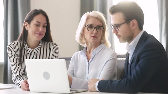 Experienced old female leader teaching mentoring business team with computer