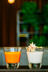 Two Glasses of Smoothie (Carrot and Orange, Apple and Coconut) in the Restaurant on Dark Background