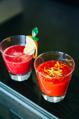 Two Glasses of Smoothie (Strawberry and Orange, Apple and Beetroot) in the Restaurant on Dark Background